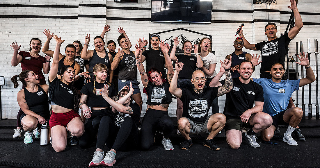 Group photo of HYROX athletes and participants at Colfax Strong celebrating together after the event with raised hands and excited expressions.